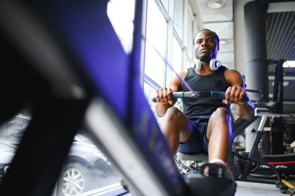 homem em uma academia, utilizando uma máquina de exercícios conhecida como remada baixa