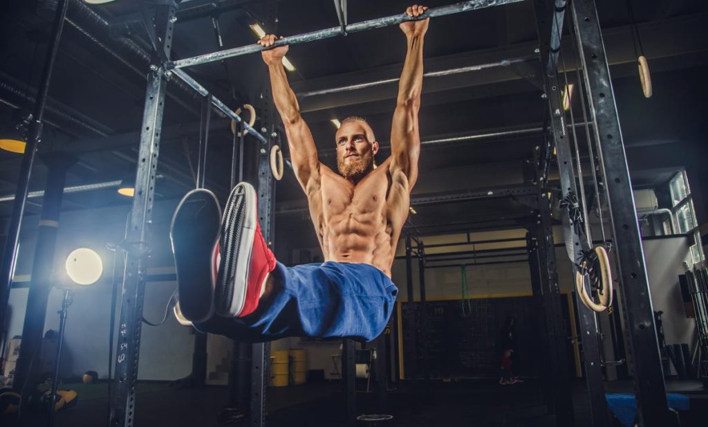 homem musculoso está realizando um exercício de calistenia na barra fixa.