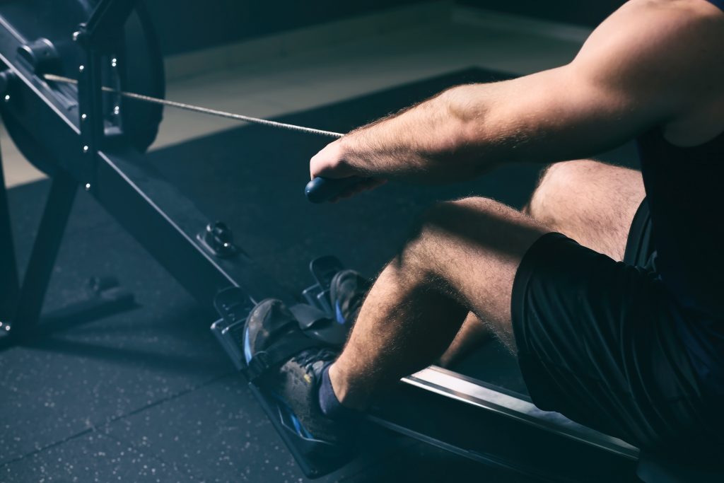 Remada baixa: como fazer corretamente e quais músculos o exercício trabalha? Pessoa realizando remada baixa em aparelho de academia, puxando o cabo em direção ao tronco durante exercício para fortalecimento das costas, bíceps e músculos posteriores.