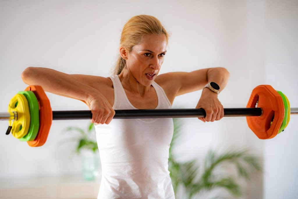 Mulher fazendo remada alta como exercícios para ombro.